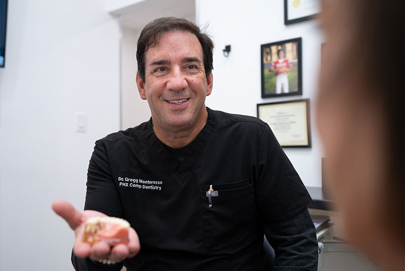 doctor holding a model of dental implants to show Patient
