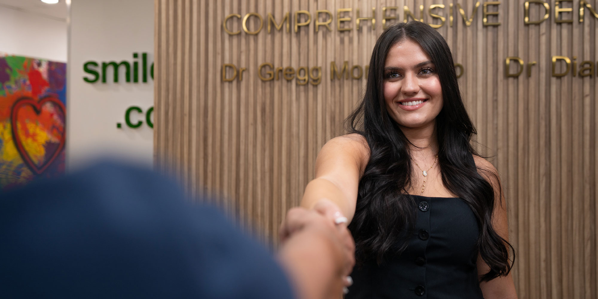 team member shaking Patients hand checking them into dental office